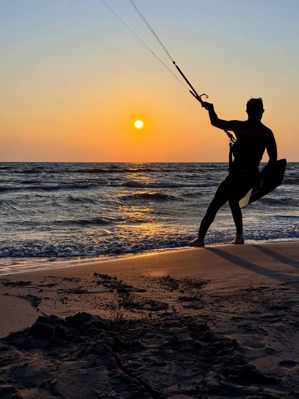 Silhouette d’un rider en kitesurf au coucher du soleil.